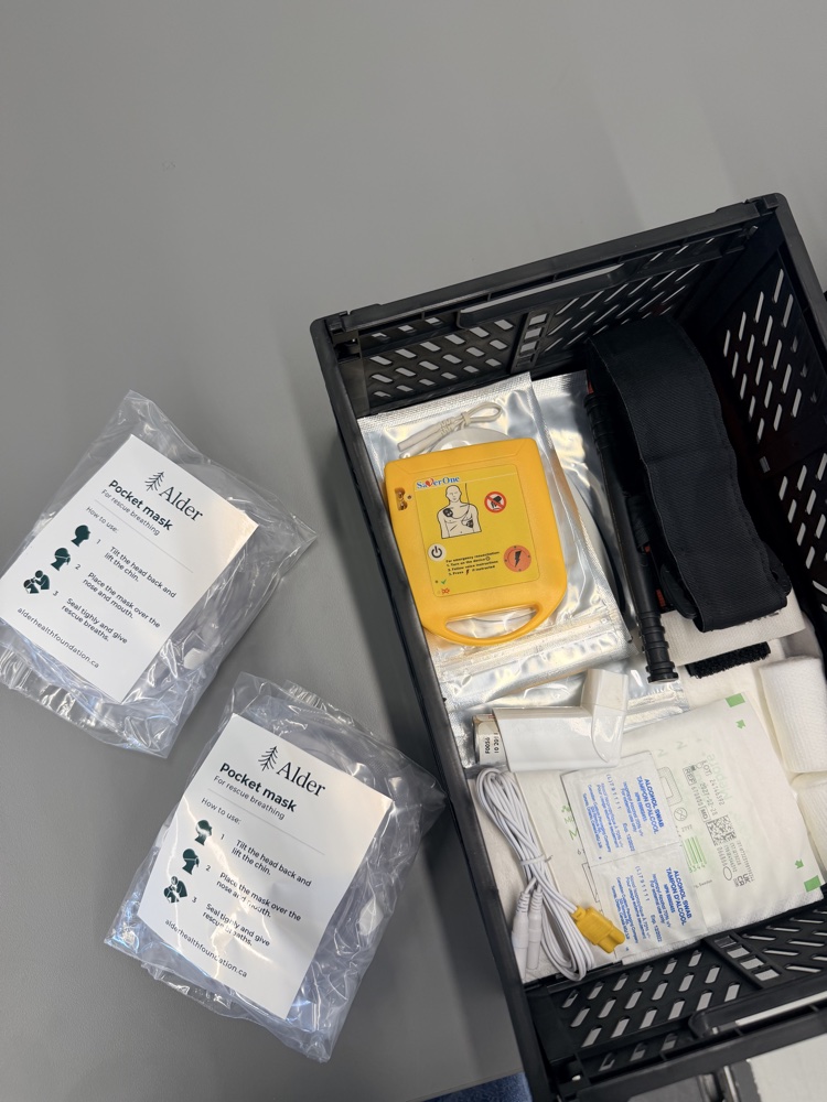 Alder-branded pocket masks, AED trainer, and first aid supplies laid out for class